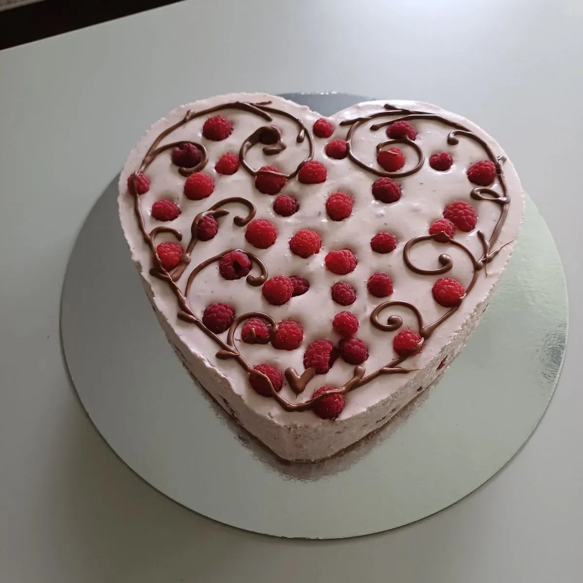 Sydämenmuotoinen vadelmakakku suklaakoristeilla